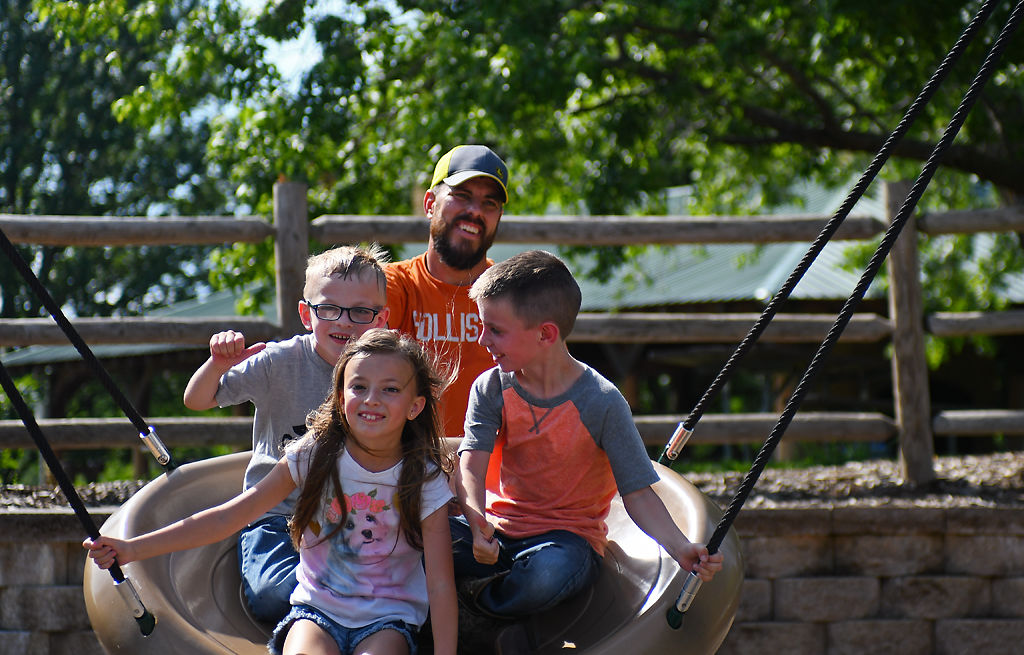 Jason Brand pushes his kids Archer, 7, Stella, 7, and Gunner, 5, on a multi-person swing